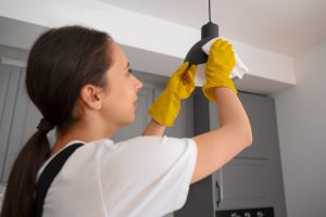 woman cleaning dusting ceiling lampshade